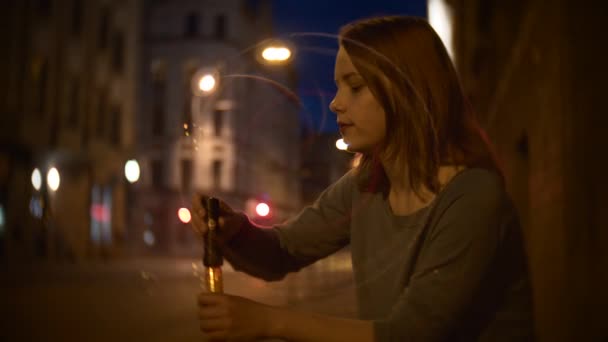 Portréja egy aranyos mosolygós tini lány, egy éjszakai város szappanbuborék fújás utcában — Stock videók