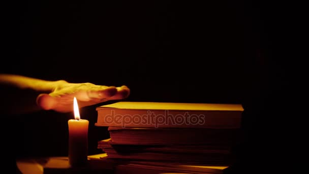 Knihy a svíčku. Oheň a kouř. Rukou nad plamen. — Stock video
