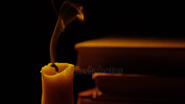 Books and candle. Fire and smoke. Light and blow out the candle. Slow motion. — Stock Video