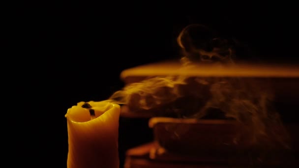 書籍やキャンドル。火と煙。光とろうそくの火を吹き消す。スローモーション. — ストック動画