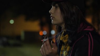 Bir kızgın üzgün genç kız ile bir sigara. Gece parkta.