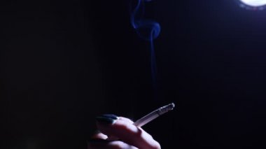 Bir sigara ve onun elinde tutan genç bir kadın.