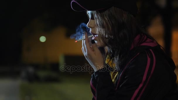 An angry sad teen girl with a cigarette. Night in park. — Stock Video