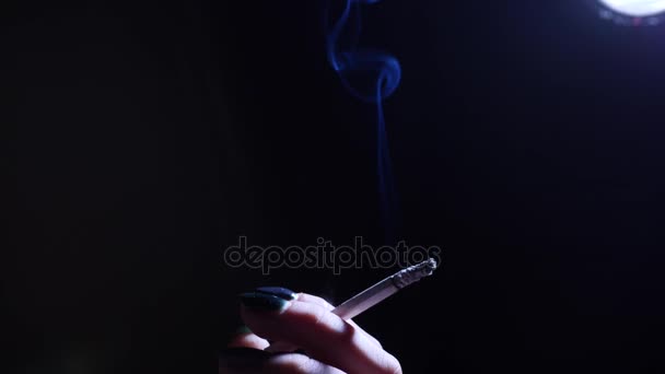 Une jeune femme fumant une cigarette et la tenant dans sa main . — Video