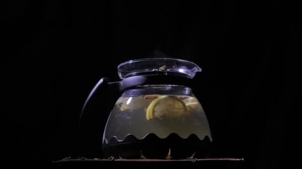 Tetera con un té caliente sobre un fondo oscuro. Pequeñas partículas similares al polvo que caen . — Vídeos de Stock