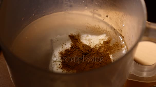 Cinamon powder falling. Close-up of mixer whipping milk smoothie with cinnamon, banana and cottage cheese. — Stock Video