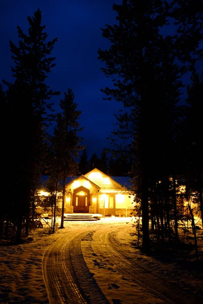 Kar ve sıcak parlayan ışıklar ile gece kış kabin — Stok fotoğraf