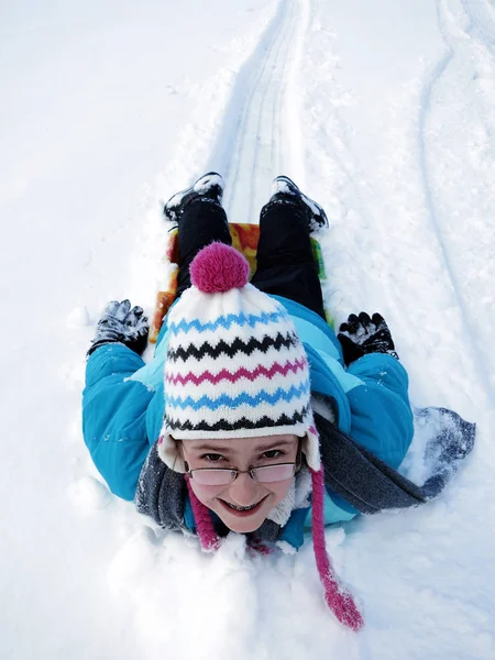 Liten flicka ner snö pulkabacke på släde snabb hastighet — Stockfoto