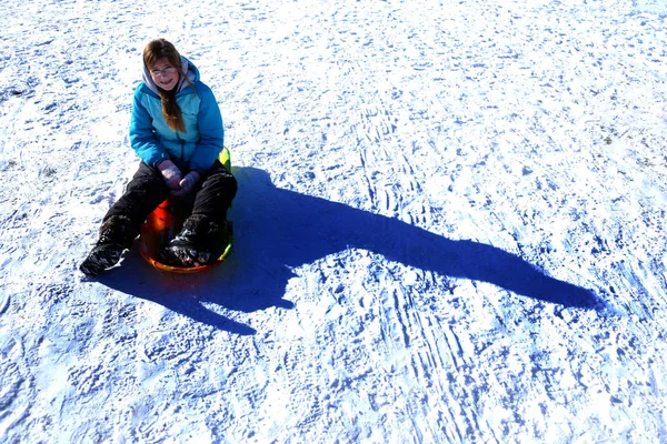 Chica joven jugando en el trineo de nieve en suelo congelado — Foto de Stock
