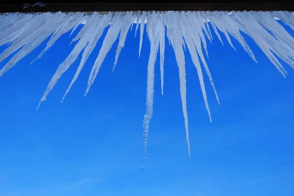 Icicli appesi al tetto della casa sciolto ghiaccio gocciolante — Foto Stock