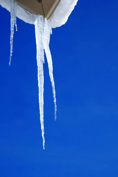 Icicli appesi al tetto della casa sciolto ghiaccio gocciolante — Foto Stock