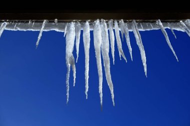 Ev çatıdan asılı buz sarkıtları erimiş buz damlama
