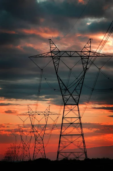 Linhas de energia para torres de metal de eletricidade e pôr do sol — Fotografia de Stock