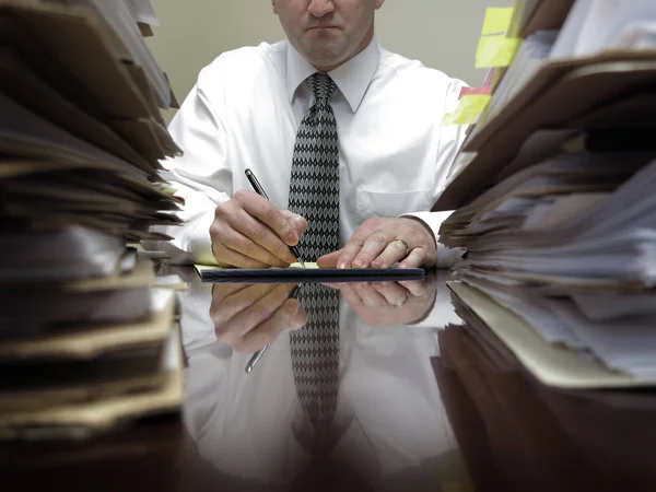 Empresario en el escritorio con montones de archivos y papeles — Foto de Stock