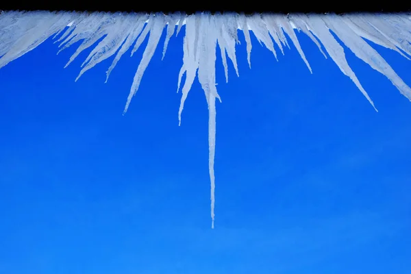 Icicles pendurados no telhado de gelo derretido em casa gotejamento — Fotografia de Stock