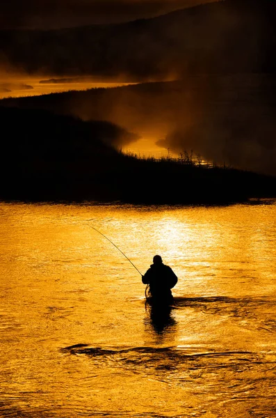 Silhouette dell'uomo Pesca a mosca nel fiume — Foto Stock