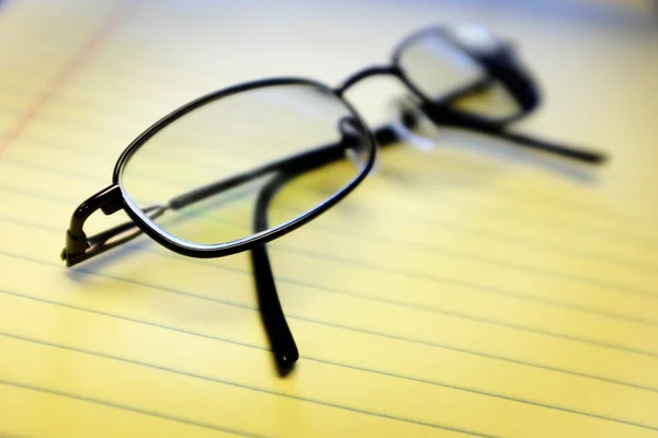 Óculos no bloco de notas amarelo no escritório — Fotografia de Stock