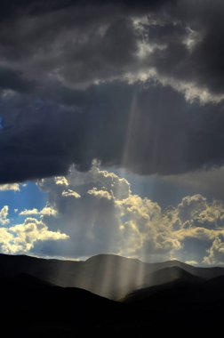 Güneş ışınları bulutlar ve dağlar