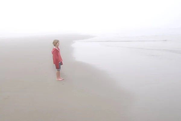 Niña en la niebla de la playa con chaqueta roja —  Fotos de Stock