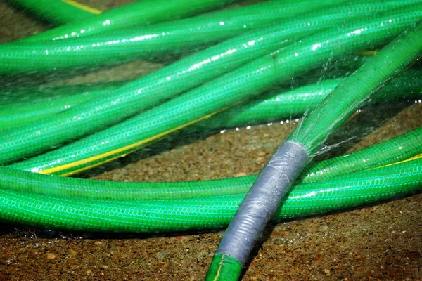 Green Hose Leaking Spraying Water