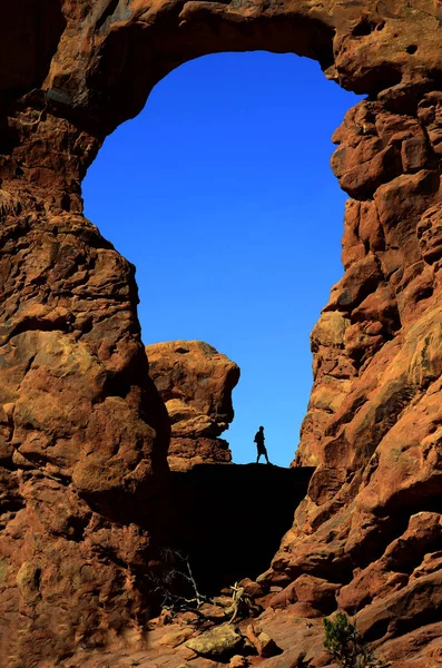 Arco nelle formazioni rocciose del canyon Silhouetter dell'escursionista — Foto Stock