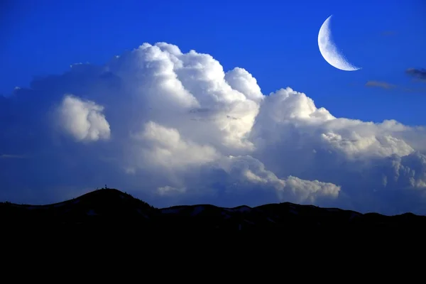 Mountains sky billowy white thunder clouds and crescent moon — Stock Photo, Image
