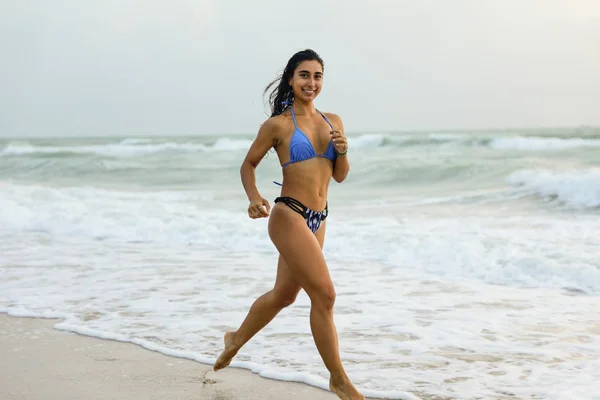 Mujer en forma corriendo en la playa en bikini en la orilla —  Fotos de Stock