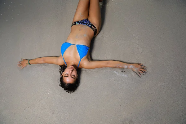 Overhead shot de um modelo de biquíni deitado na areia — Fotografia de Stock