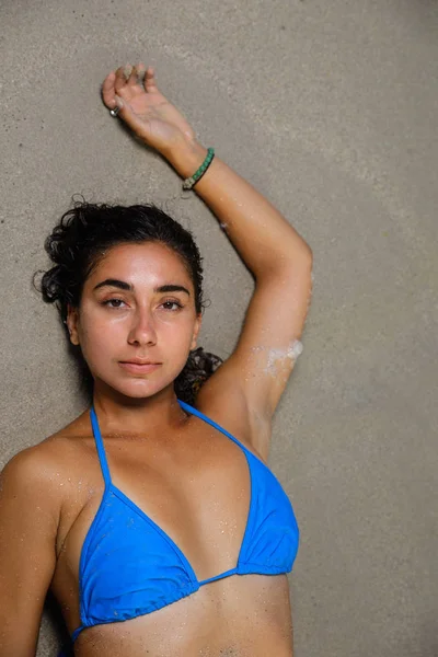 Femme couchée sur le sable avec le bras tendu au-dessus de la tête et looki — Photo