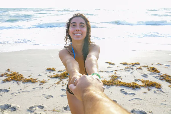Женщина держит песок за руку и тянет к океану — стоковое фото