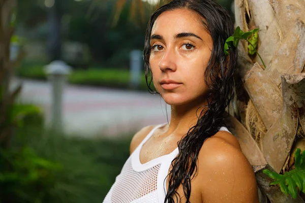 Woman posing wet after swimming leaning on a palm tree — Stock Photo, Image