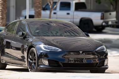 Şehirde park etmiş siyah bir Tesla Modelinin fotoğrafı.