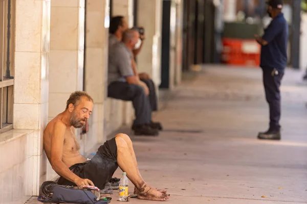 Obdachloser Sitzt Auf Der Straße Inmitten Wokrender Männer Hintergrund — Stockfoto