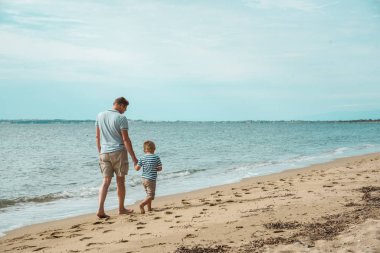 Baba oğul deniz kenarında yürüyorlar.