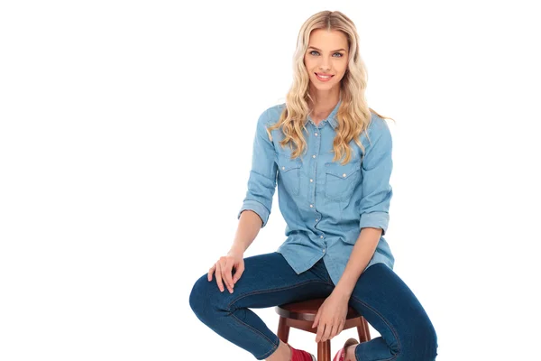 Happy young casual woman in jeans clothes sitting on chair — Stock Photo, Image