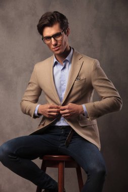 oturma ve ceketini unbuttoning gülümseyen iş adamı
