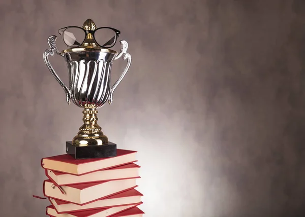 Prêmio campeão estudante com óculos em pilha de livros — Fotografia de Stock