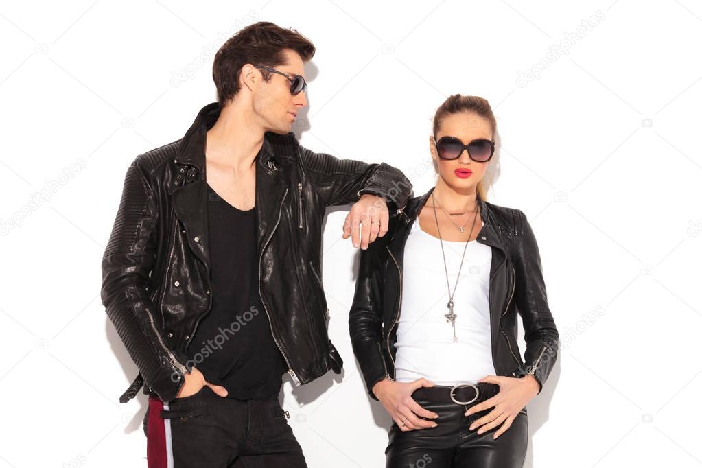 man in leather jacket leaning elbow on girlfriend's shoulder