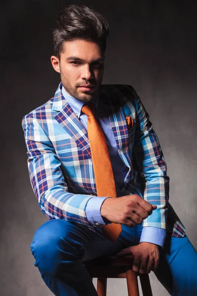 Ernsthafter junger Geschäftsmann im karierten Anzug sitzend — Stockfoto