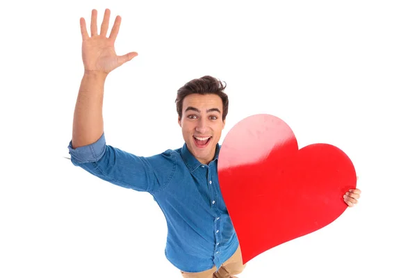 Amazed young man holding a red heart — Stock Photo, Image