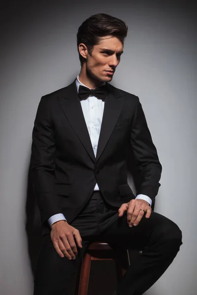 Vista laterale di un uomo elegante che indossa smoking seduto — Foto Stock
