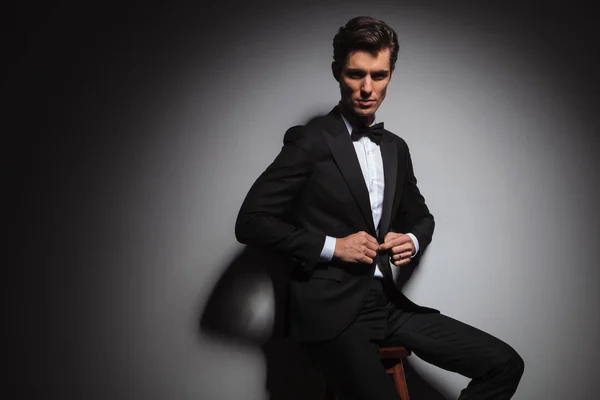 Sitzend eleganter Geschäftsmann im Smoking, der seinen Mantel zuknöpft — Stockfoto