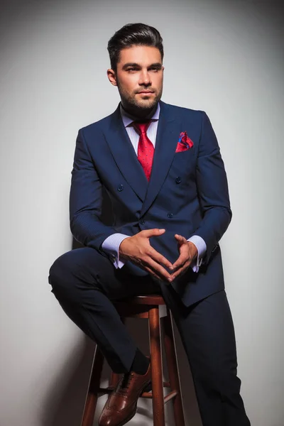 Sitzender junger eleganter Mann in Anzug und Krawatte, der wegschaut — Stockfoto