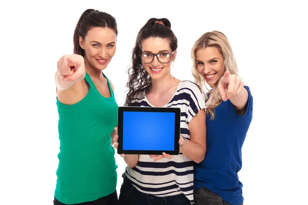 Три жінки, що представляють порожній екран планшета і вказують — стокове фото