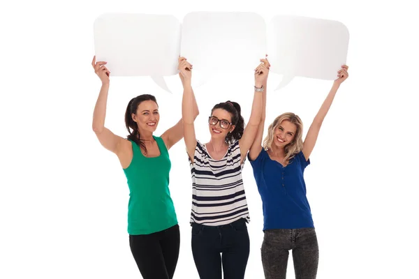 Tres mujeres felices sosteniendo burbujas de habla en blanco sobre sus cabezas — Foto de Stock