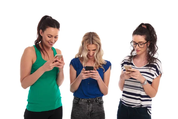 Lachende junge Frauen, die Textnachrichten auf ihren Telefonen lesen — Stockfoto