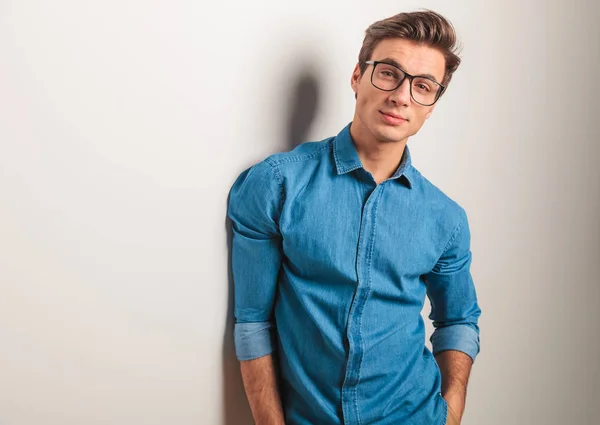 Cool young casual man leaning his shoulder on wall — Stock Photo, Image