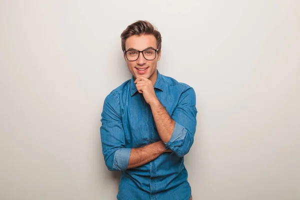 Homem usando óculos, sorrindo e tocando seu queixo — Fotografia de Stock