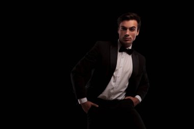 Elleri ceplerinde ile poz smokin giyen serin şık adam 