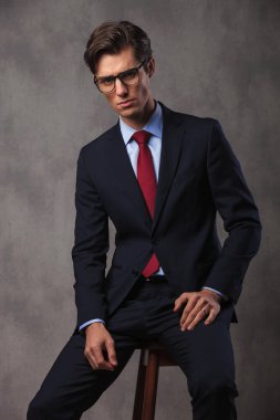 bir taburede oturan ciddi genç iş adamı